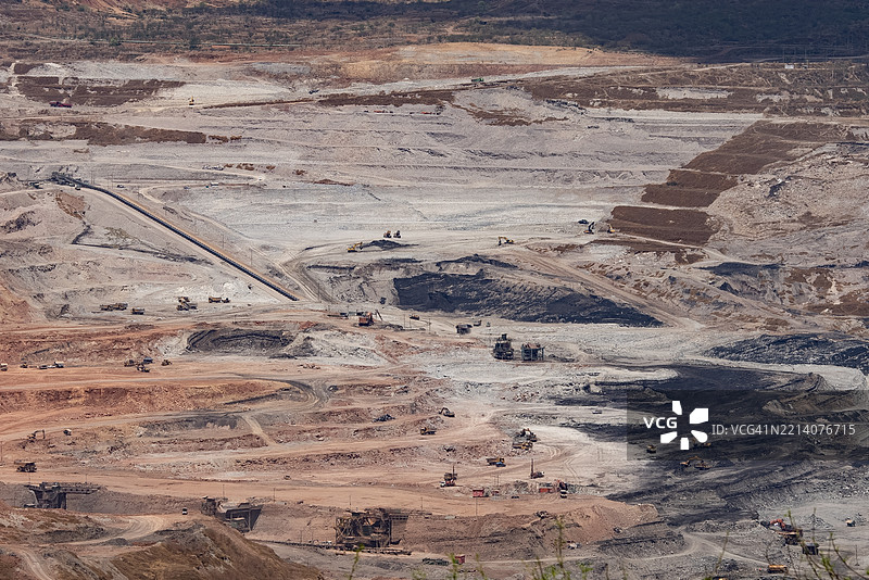 大型露天矿场的鸟瞰图，展示了输送带和工业机械正在挖掘土壤和矿物。图片素材