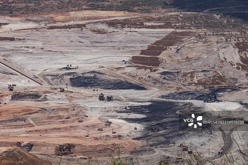 大型露天矿场的鸟瞰图，展示了输送带和工业机械正在开采土壤和矿物。图片素材