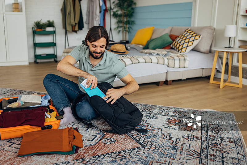 一个男人把文件、护照和机票放进背包里图片素材