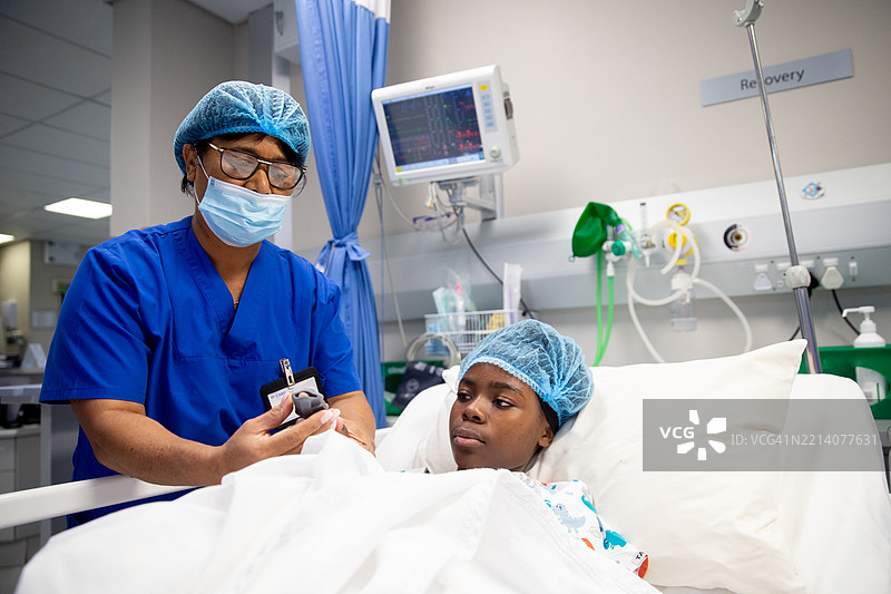 年轻患者在麻醉后恢复室接受脉搏监测夹具。图片素材