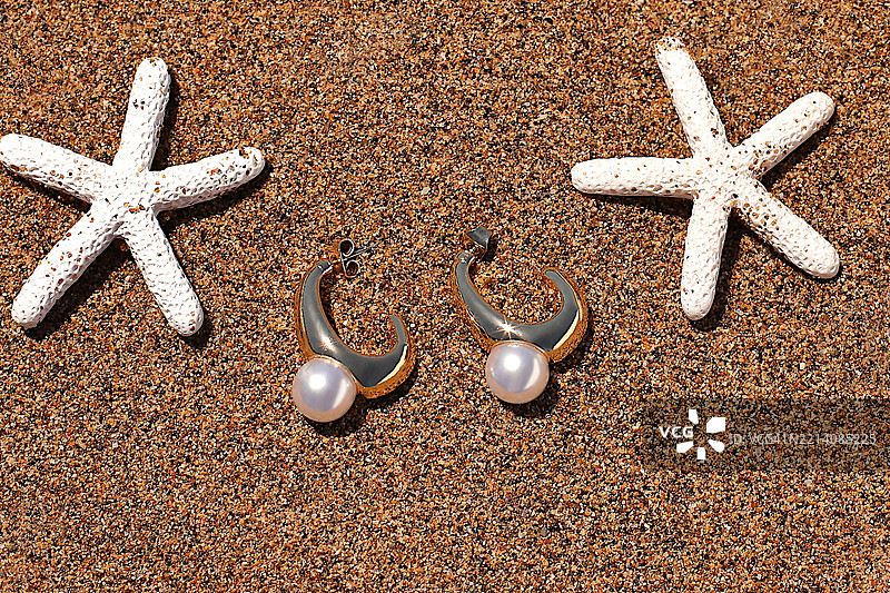 沙滩上的金色和珍珠耳环与贝壳，夏季海滩配饰，西班牙图片素材