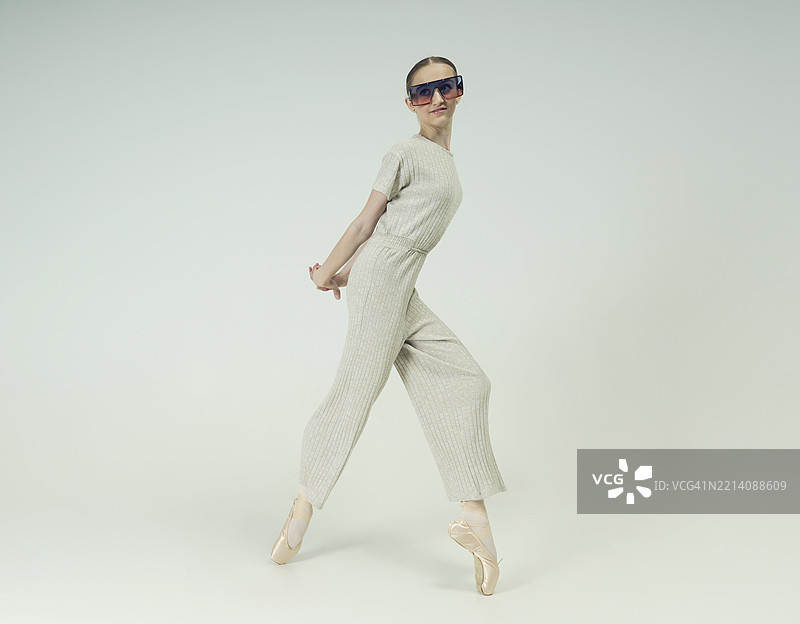 年轻的青少年芭蕾舞者在摄影工作室中摆姿势，穿着时尚的连体衣，展现舞蹈元素。图片素材