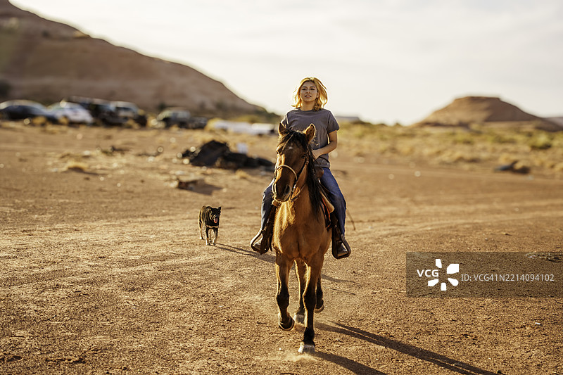 浅景深的美丽纳瓦霍女孩骑马在亚利桑那州纪念碑谷附近的沙漠中，位于美国西南部。图片素材