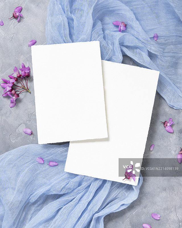 灰色背景上野生紫色花朵旁的垂直空白卡片，春季婚礼样板的俯视图图片素材