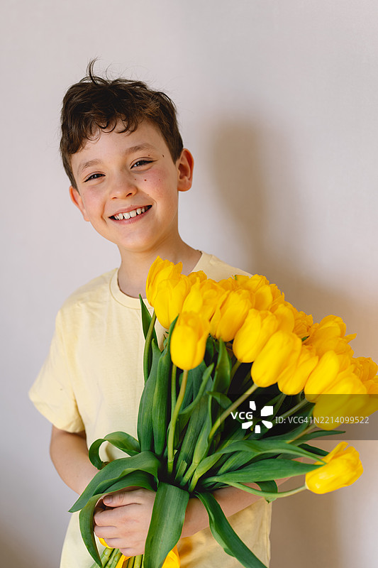 孩子快乐地捧着一束鲜艳的黄色郁金香图片素材