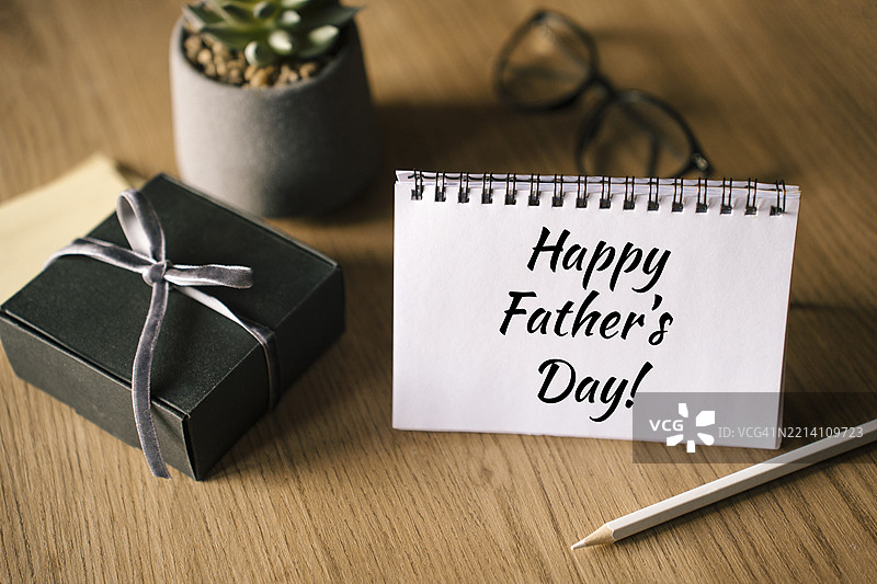 父亲节假日概念，桌上有打开的日历手机、眼镜、笔记本和铅笔。图片素材