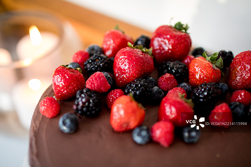 新鲜巧克力蛋糕配上光滑的浆果和烛光图片素材