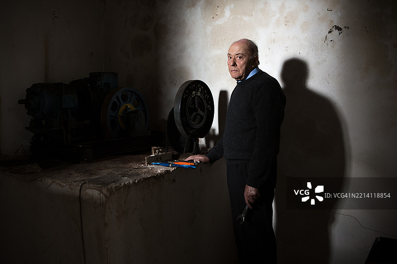 在昏暗的车间里工作的老年人图片素材