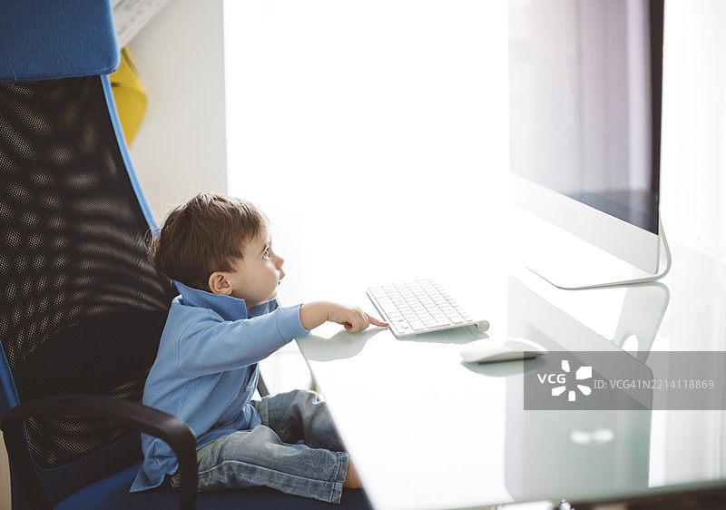 年轻孩子在家中的工作站使用电脑图片素材