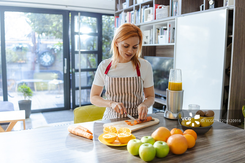 女性在明亮现代的居住空间中准备新鲜果汁图片素材