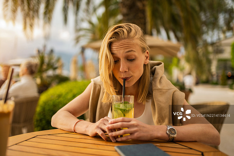 年轻女性在海滨度假村的街头咖啡馆享受饮品图片素材