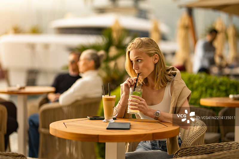 年轻女性在海滨度假村的街头咖啡馆享受饮品图片素材
