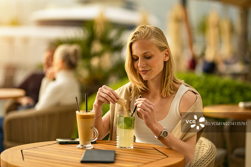 年轻女性在海滨度假村的人行道咖啡馆放松。图片素材