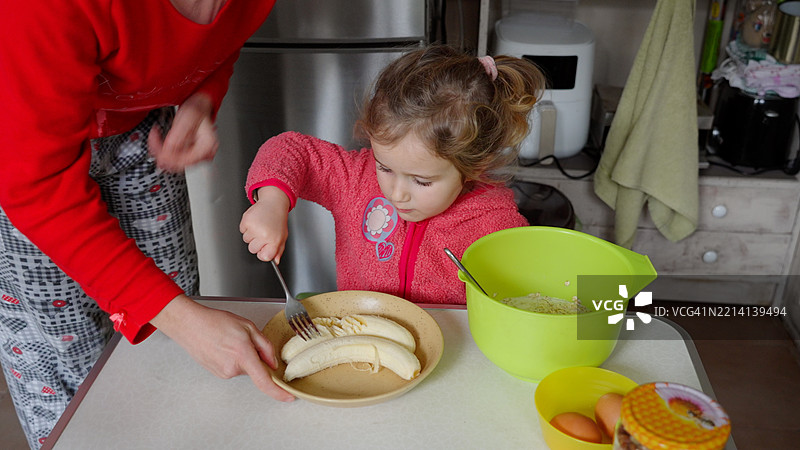 孩子与妈妈一起做蛋糕，促进儿童发展与学习。图片素材