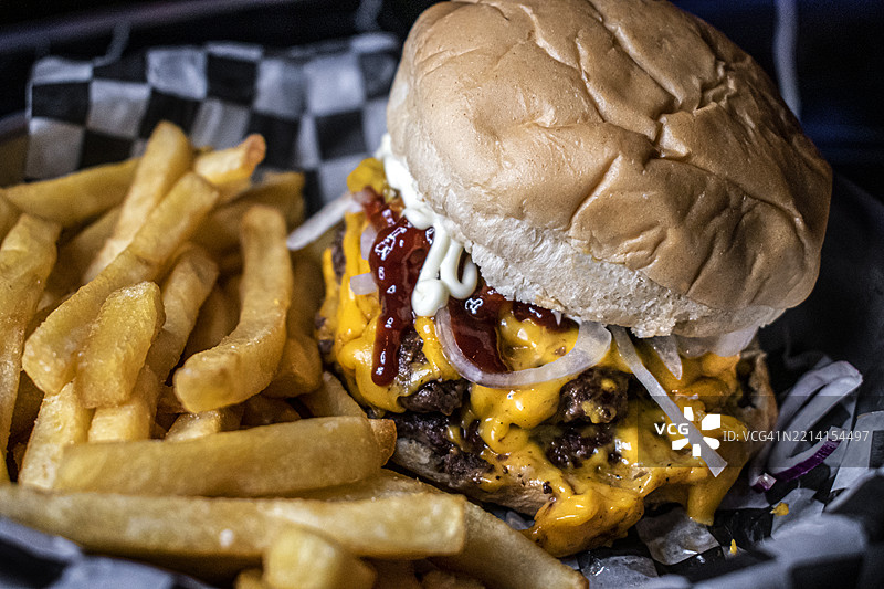 双层切达奶酪汉堡，洋葱，配料和薯条 - 美食图片素材