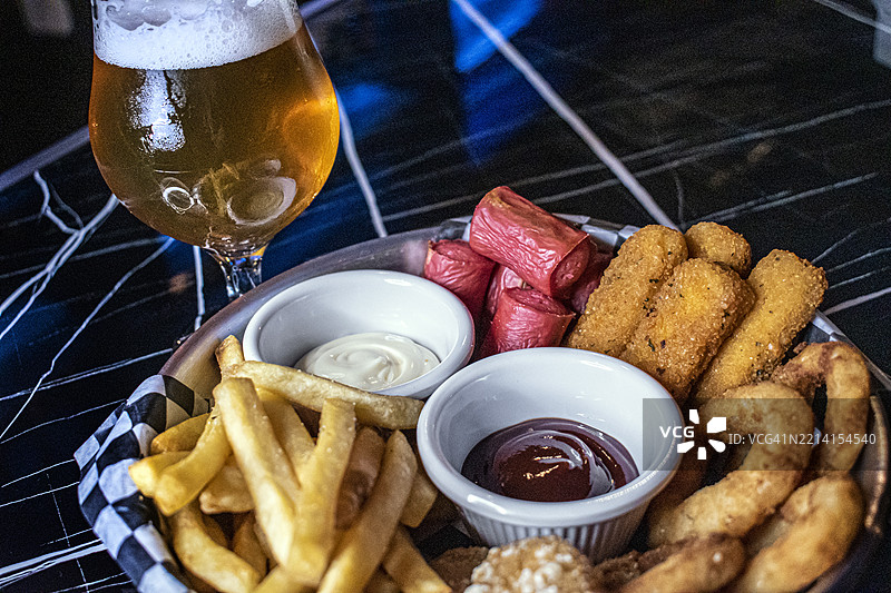薯条、香肠、马苏里拉奶酪条、面包圈洋葱圈和一杯手工啤酒 - 美食图片素材