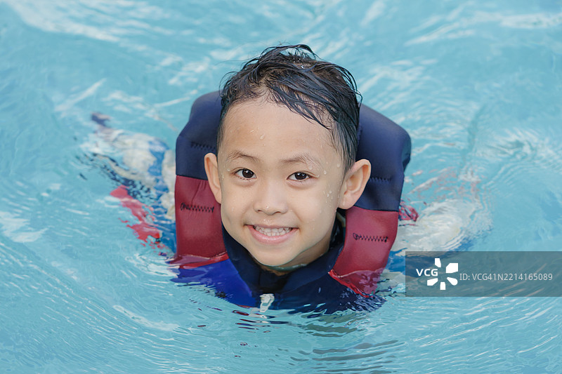 亚洲男孩在游泳池里玩得很开心。图片素材