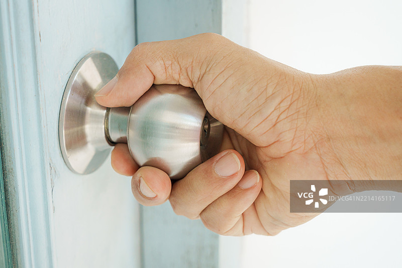 男人的手握着门把手。图片素材