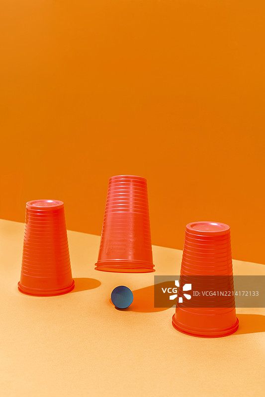 玩三只红色塑料杯和一个蓝色球的壳游戏或杯子游戏图片素材