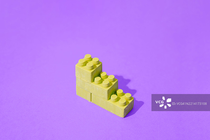 紫色背景上由玩具积木组成的黄色上升堆叠图片素材