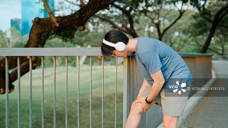 亚洲年轻男子在跑步时感到膝盖疼痛图片素材