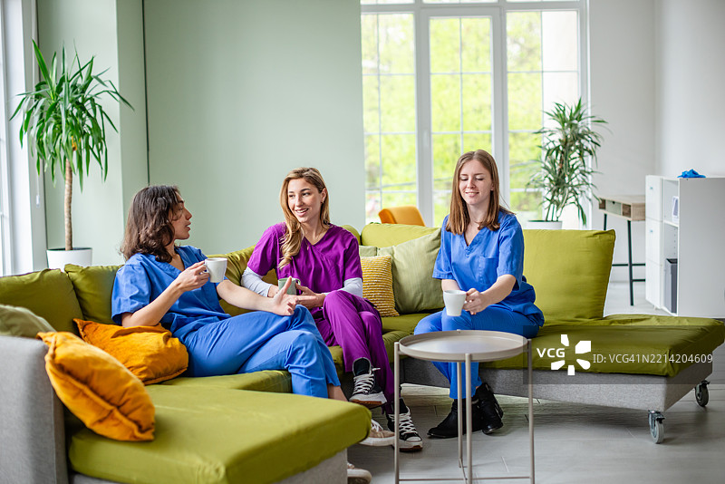 年轻女性医护人员在现代医疗设施中休息并聊天图片素材