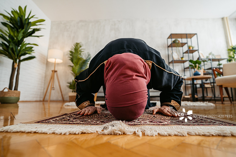 年轻穆斯林女性在家中使用祷告垫祈祷图片素材