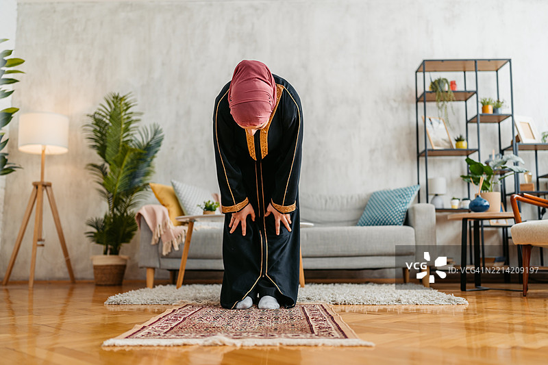 年轻穆斯林女性在家中使用祷告垫祈祷图片素材