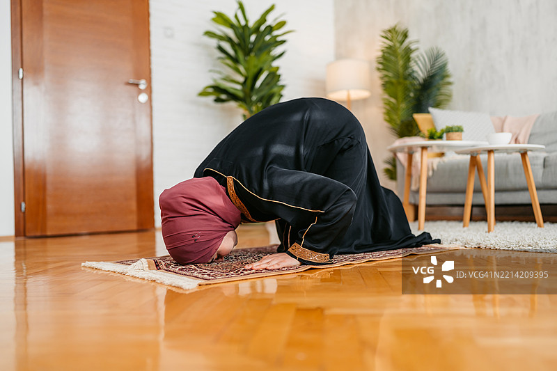 年轻穆斯林女性在家中使用祷告垫祈祷图片素材