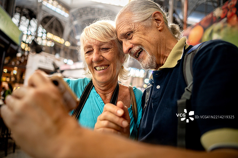 老年游客夫妇在市场上使用手机图片素材