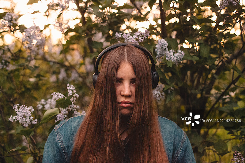 年轻女性在春天戴着耳机听音乐图片素材