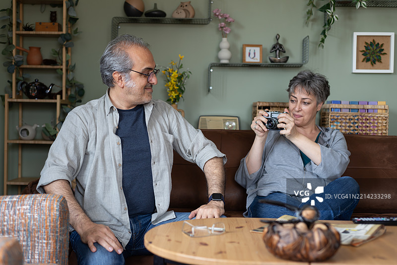 两位退休老人坐在沙发上研究一台复古相机。他们准备拍几张照片。图片素材