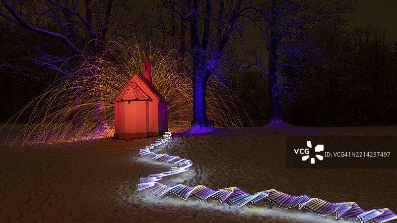 在雪地中，圣安娜教堂前的光绘，五彩斑斓的光效环绕着火花，位于德国巴伐利亚州的明德尔海姆，乌特阿尔高区。图片素材