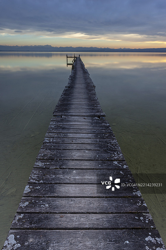 长长的木栈道延伸过一湖如镜的湖面,营造出宁静的傍晚氛围,阿默湖,斯塔恩贝格区,巴伐利亚,德国,欧洲图片素材