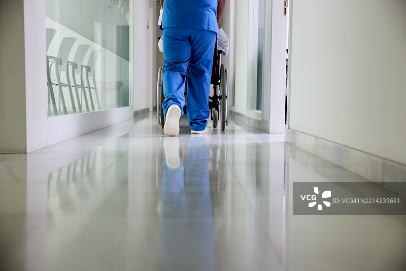 一名护士在医院走廊推着轮椅。图片素材