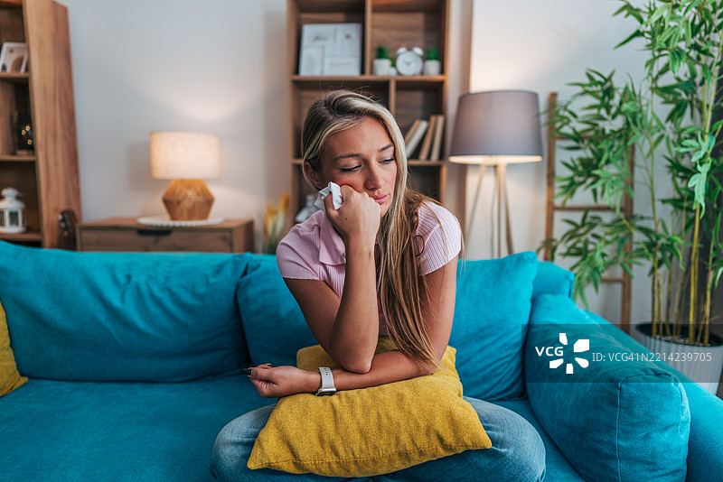 伤心的年轻女性在家里的沙发上哭泣图片素材