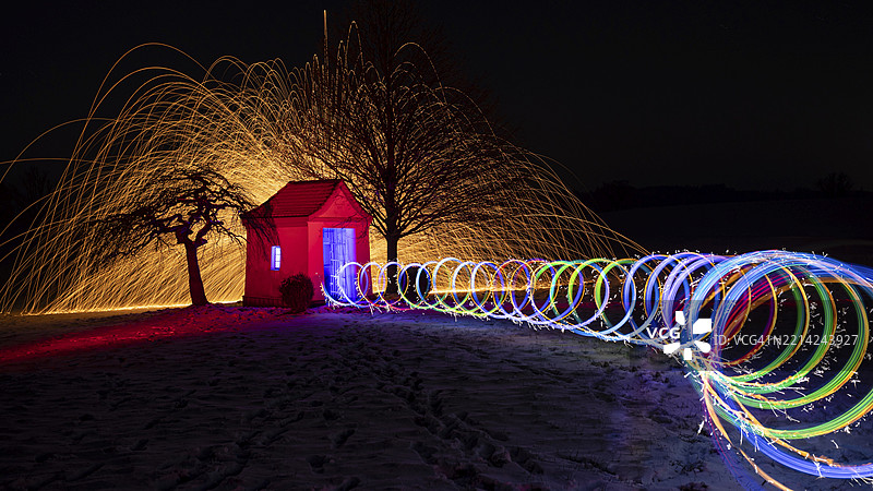 在冬季黑暗中，教堂前的圆形彩色图案光绘，喷洒出火花，巴伐利亚州，德国，欧洲，埃格尔霍芬附近的田野教堂。图片素材