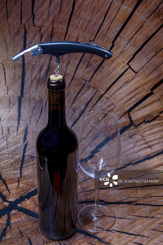 酒瓶、开瓶器和空酒杯放在木质背景上，准备品尝图片素材