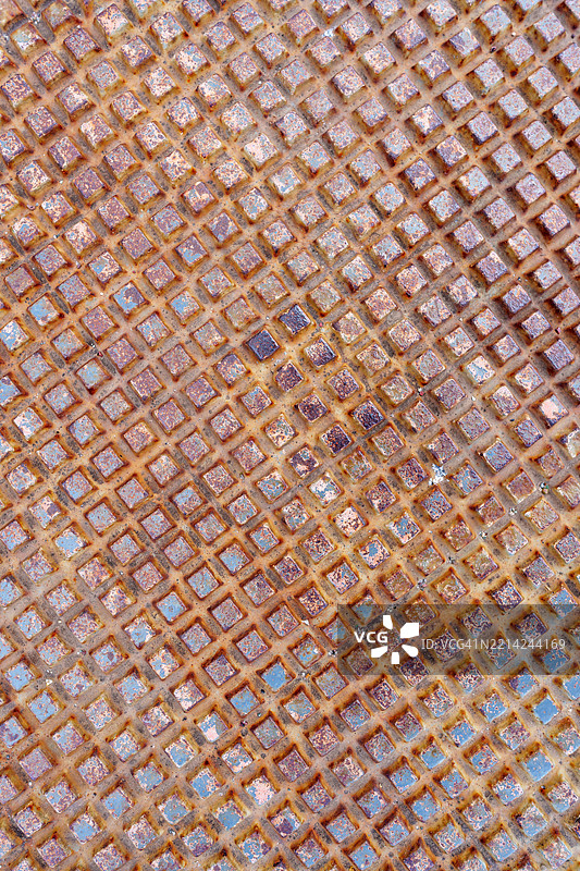 生锈的金属表面带有菱形图案，形成了有纹理的背景图片素材