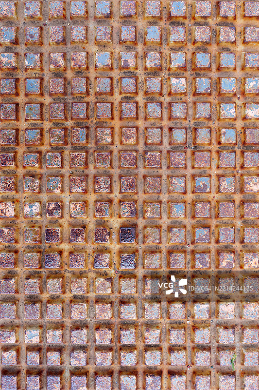 生锈的金属表面上有一个方形凸起的网格，形成规则的图案图片素材