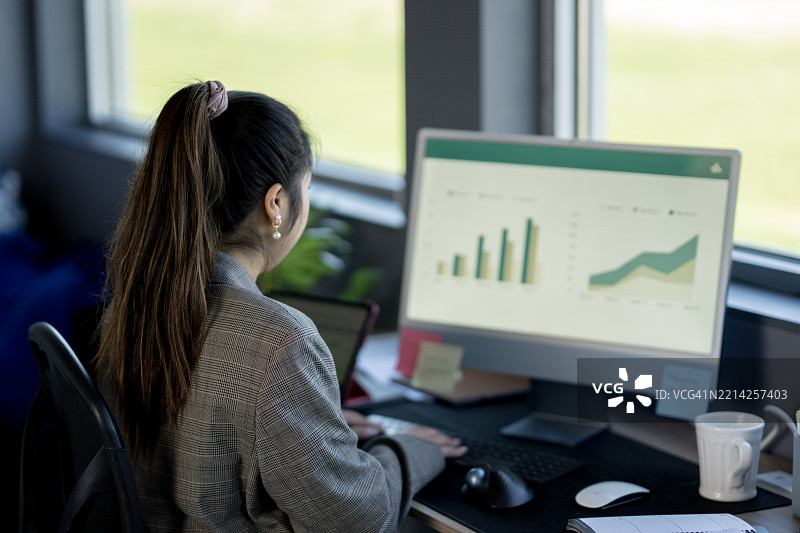 女商人在办公室环境中使用桌面电脑分析财务数据图片素材
