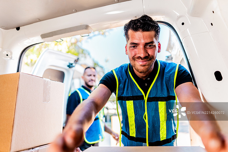 年轻的送货员正在拆卸货车上的包裹图片素材