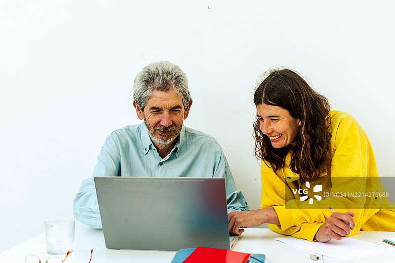 同事们在办公室里微笑着一起使用笔记本电脑工作图片素材