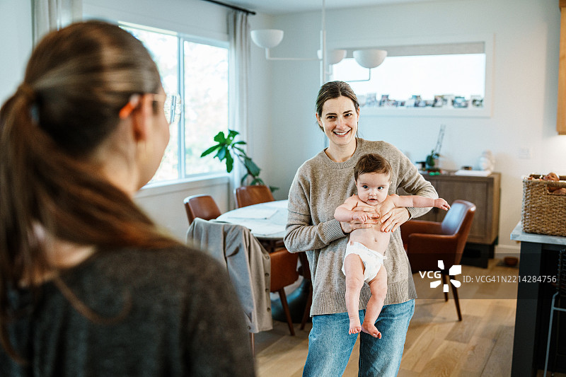 母亲在家中抱着她的宝宝，与物理治疗师会面图片素材