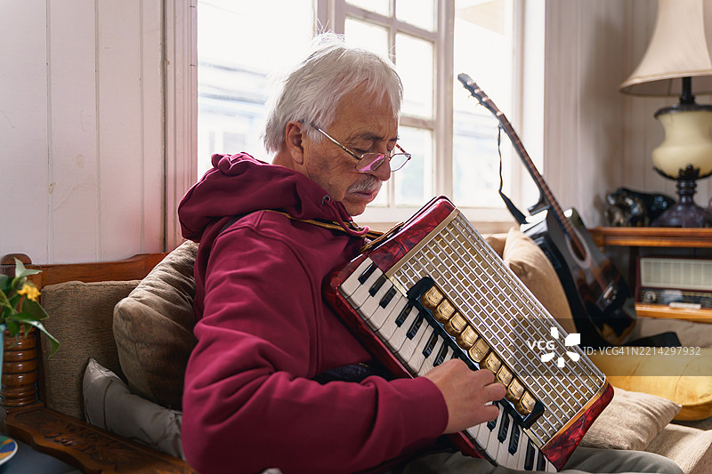 拉丁美洲资深音乐家在家中演奏手风琴图片素材
