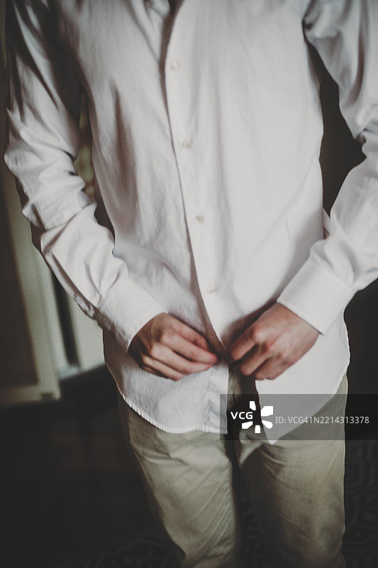 男性在镜子前扣白衬衫的特写镜头图片素材