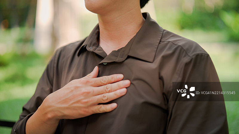 年轻的亚洲男子因感到疼痛和身体不适而按压胸部。图片素材