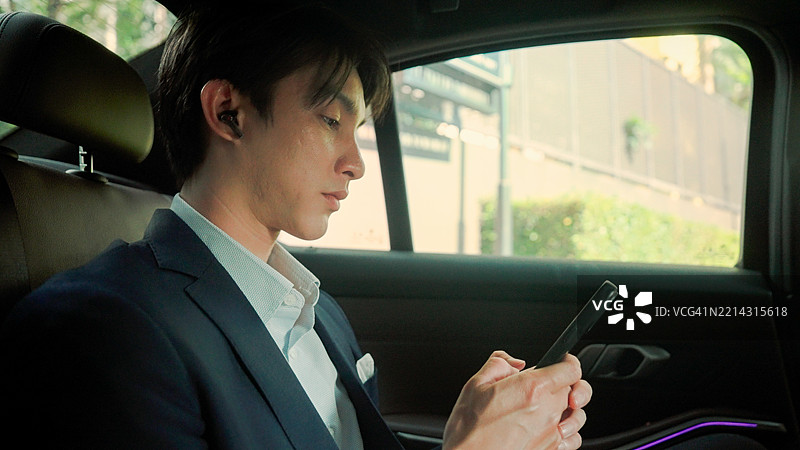 年轻的亚洲男子在车上给客户发送商务信息。图片素材