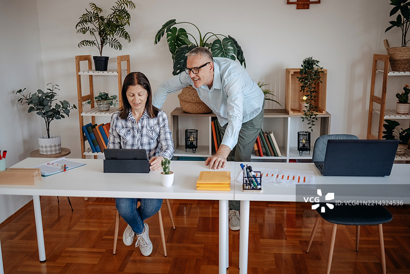 两位同事在办公室里边工作边交谈图片素材