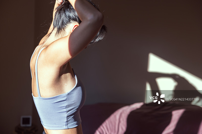 年轻女性在卧室里沐浴在晨光中。图片素材